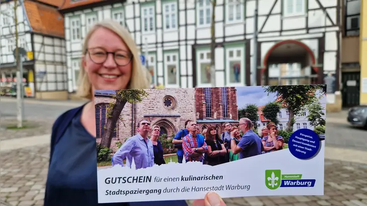 Carmen Rütters-Engemann mit dem Gutschein für die kulinarischen Spaziergänge, bei denen die Teilnehmer Warburg mit allen Sinnen genießen können. (Foto: Stadt Warburg)
