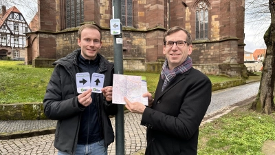 Touristiker Lucas Lambracht (links) und Bürgermeister Tobias Scherf präsentieren die neuen Wege-Markierung und den überarbeiteten Flyer der Tour der Sehenswürdigkeiten an der Neustadtkirche.<br><br>  (Foto: Stadt Warburg)